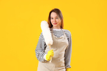 Wall Mural - Young woman with pp-duster on yellow background