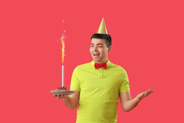 Wall Mural - Happy young man with birthday cake on red background