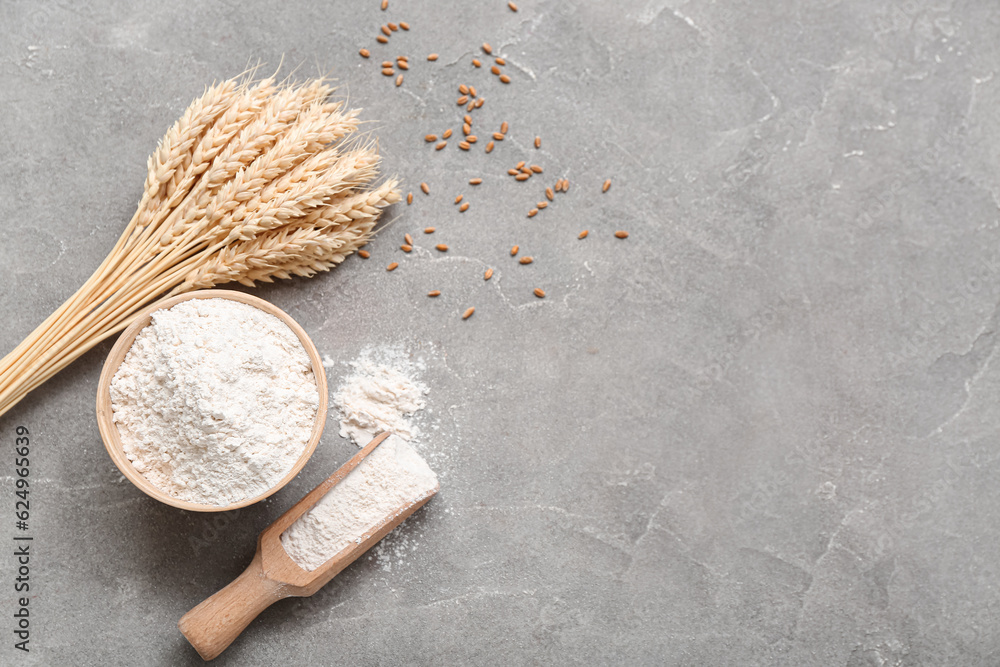 Bowl and scoop with wheat flour on grey grunge table