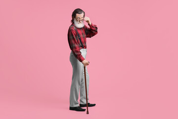 Wall Mural - Senior man with walking cane on pink background