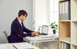 © Studio Romantic - Businessman calculates business report, reviews company statistics, studies financial and marketing data. Man sits with calculator in front of laptops with graphs and spreadsheets open on screen.