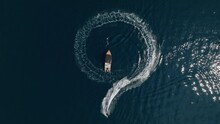 Top Down Aerial View Men On Electric Surf Board Making Circle Around The Luxury Boat On The Blue Water Sea.