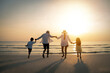 © Garun Studios - Family, travel, beach, relax and lifestyle, holiday concepts. Happy Family are having fun at beach in sunset. Parents are holding hands their children and walking on the beach at sunset in holiday.