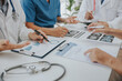 © Witoon - Medical analysts and physicians consult documents on graphs, data and charts in a hospital conference room.