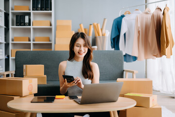 Startup small business SME, Entrepreneur owner woman using smartphone or tablet taking receive and checking online purchase shopping order to preparing pack product box. .