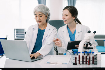 medical research laboratory: two scientists working, using digital tablets, analyzing samples, talki