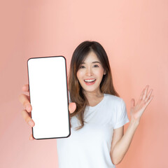 beautiful Asian young woman showing big smart phone with blank screen , white screen empty copy space for advertising banner isolated on pink background , Mock Up Image