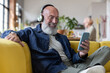 © ReeldealHD images - Cool senior man at home using a smartphone with headphones to listen to music