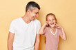 © sementsova321 - Happy carefree family father and daughter wearing casual t-shirts standing isolated over beige background laughing with extremely cheerful faces enjoying time together.