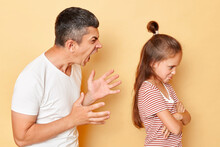 Father Punishing His Daughter, Domestic Violence, Young Man Screaming On Little Girl With Aggression And Anger Standing Isolated Over Beige Background.