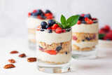 Vegan dessert in a glasses with berries, mint, nuts, whipped cream and biscuit. Healthy food, sugar, gluten and lactose free.