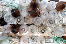 Overhead Shot Of Empty Uncapped Bottles On Wooden Plank With White Sand Scattered All Over It