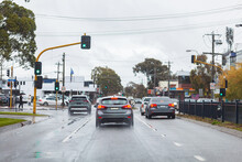 Traffic Lights At Intersection With Cars On Rainy Wet Day With Slippery Hazardous  Roads