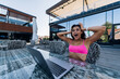 Cute young woman in swimsuit is shocked working on laptop sitting on terrace on the beach