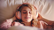 © ADDICTIVE STOCK - Generative AI illustration top view of sleeping young woman lying on soft pillow an listening to music in headphones