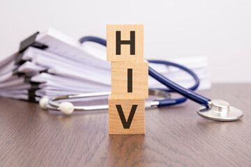 Poster - text HIV written on wooden cubes near a stethoscope on a paper background. HIV - human immunodeficiency virus, medical concept