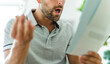 © Louis-Paul Photo - Worried middle-aged man reading unexpected paper document.