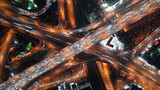 Top-down view of fast-moving cars on a highway, intense traffic during rush hour at a city crossroad, modern multi-level intersection with beautifully moving vehicles.
