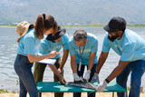Fototapeta Uliczki - group of diverse volunteer  and professional biologist team working together to research injecting microchip into the fish's body to track its movements and behavior
