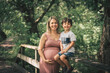 © Louis-Paul Photo - Pregnant woman posing in a green garden with his child boy