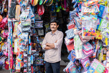 Indian Roadside Toy Shop Vendor, Seller Standing In Front With Currency Or Smartphone