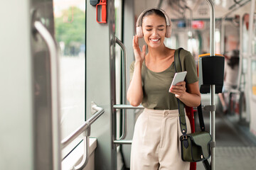 Wall Mural - Woman In Tram Holding Phone Listening Music In Earphones Inside