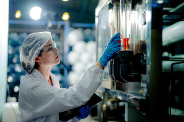 scientist worker checking the quality of Reverse osmosis machine system at the industrial factory. Female worker recording data at the control panel with measure pressure for recycle portable plant.