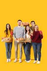 Group of friends with tasty pizza and drinks on yellow background