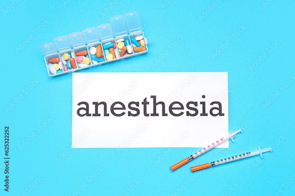 Paper with word ANESTHESIA, pills and syringes on blue background