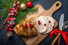 Christmas Baked Ham Sliced With Red Berries And Festive Decorations On Wooden Cutting Board, Dark Rustic Background From Above. Christmas And New Year Holiday Dinner With Baked Pork