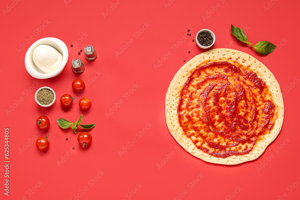 Pizza crust with tomato sauce and ingredients on red background