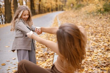 Wall Mural - Mother and her daughter playing and having fun in autumn forest