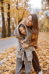 Wall Mural - Mother and her daughter playing and having fun in autumn forest