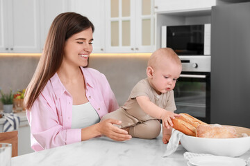 Wall Mural - Happy young woman and her cute little baby spending time together in kitchen