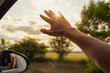 © kieferpix - Person driving on country road with hand outstretched to the sunlight feeling happy enjoying summer road-trip