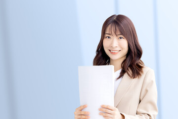 書類を揃えて持つ笑顔の日本人ビジネスウーマン