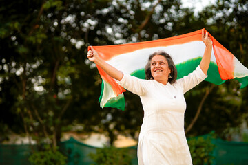 Indian senior woman waving tricolor cloth or odhani. celebrate national festival.