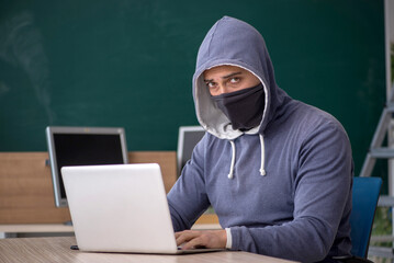 Wall Mural - Young male hacker sitting in the classroom