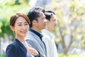 Poster - 屋外の新緑の前に立つビジネスマンたち