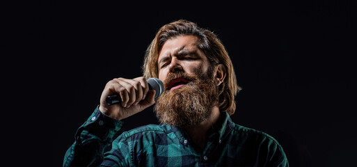 Wall Mural - Bearded man singing with microphone. Male singing with a microphones. Man with a beard holding a microphone and singing. Bearded man in karaoke sings a song into a microphone. Male attends karaoke