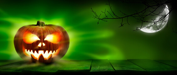 Wall Mural - a spooky halloween pumpkin, jack o lantern, with an evil spinning green aura glow on a wooden table 