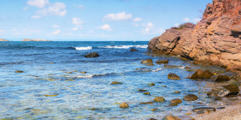 Wall Mural - rocky coast at the black sea. calm summer scenery in warm afternoon light. island in the distance beneath a sky with fluffy clouds