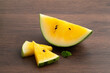 Sliced yellow watermelon in a plate on wooden table background.