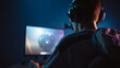 © bornmedia - Back view of man wearing headphones and playing game on screen monitor