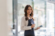 © Natee Meepian - Asian woman barista holding tablet for checking order from customer on blurred coffee cafe shop background , SME business concept