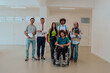© Minet - A group of students with a professor and a colleague who is in a wheelchair are standing together in the corridor of a modern university