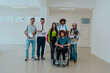 © Minet - A group of students with a professor and a colleague who is in a wheelchair are standing together in the corridor of a modern university