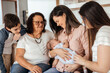 © kleberpicui - Multi-generation family sitting on sofa with newborn baby