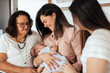© kleberpicui - Multi-generation family sitting on sofa with newborn baby