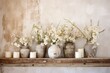 © The 2R Artificiality - This home decor features white flowers displayed in vases of neutral colors, alongside candles that have been burned, all placed on a rustic wooden shelf against a shabby white wall.